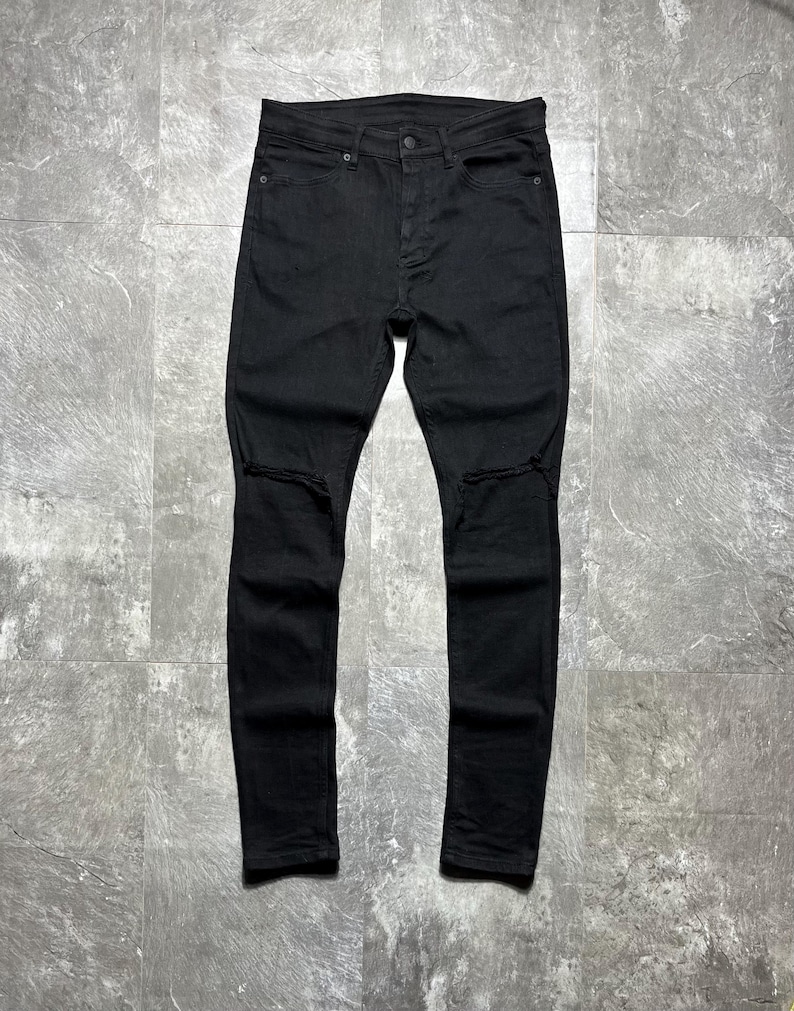 Op de afbeelding: Zwarte denim jeans met distressed kniedetails. De jeans hebben een klassiek vijf-zakken ontwerp, een knoop- en ritssluiting en een slanke pasvorm. De donkere wassing geeft ze een veelzijdige uitstraling.