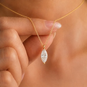 Op de afbeelding: Een fijne gouden ketting met een enkele, in marquise geslepen, heldere edelsteen als hanger. De hanger wordt vastgehouden door een klein gouden oogje en hangt verticaal aan de dunne, gepolijste gouden schakelketting voor een eenvoudig sieraad.