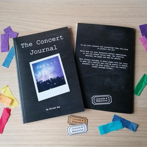 Op de afbeelding: Twee zwarte tijdschriften, "The Concert Journal", met een concertfoto op de omslag, en de andere met tekst. Bevat extra pagina's, leuke lijsten en een setlist poster. Gekleurde papieren stukjes en stickers zijn verspreid.