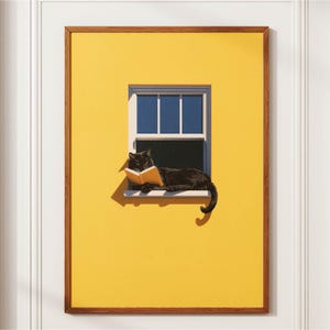 May include: A framed wall art print featuring a solid bright yellow wall with a single window. A black cat is lying on the window sill, holding an open light-colored book with its paws. The scene is illuminated by sunlight, casting a sharp shadow.