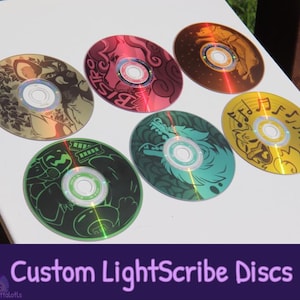 May include: Six circular optical discs featuring custom graphic designs in various colours including gold, pink, brown, green, teal, and yellow. Each disc displays unique illustrations of animals and musical notes with a reflective surface finish.