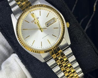 Orologio automatico da uomo Seiko 5 con lunetta scanalata, modello 7009-3111, con indicazione di giorno e data.