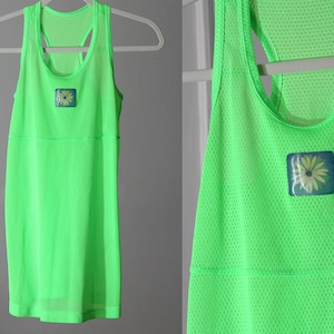 Peut inclure: Un débardeur vert vif en tissu maillé avec un petit motif de fleur sur le devant.