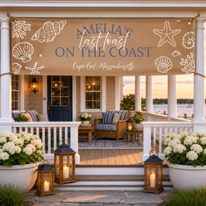 May include: A tan banner with white seashell illustrations and the text "Amelia's Last Toast on the Coast" and "Cape Cod, Massachusetts" hangs above a porch. The porch features lanterns, seating, and white columns.
