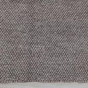 May include: Close-up of a gray textured rug. The rug has a dense, nubby texture, with small, rounded bumps covering the surface. The color is a muted gray, with variations in tone creating visual interest. The rug's edge is visible.