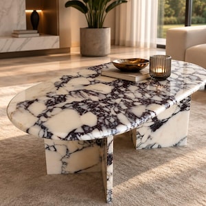 May include: An oval coffee table featuring a polished white and deep purple marble surface with a distinct veined pattern. The table is supported by a sturdy, matching marble base with intersecting panels that provide a stable foundation.