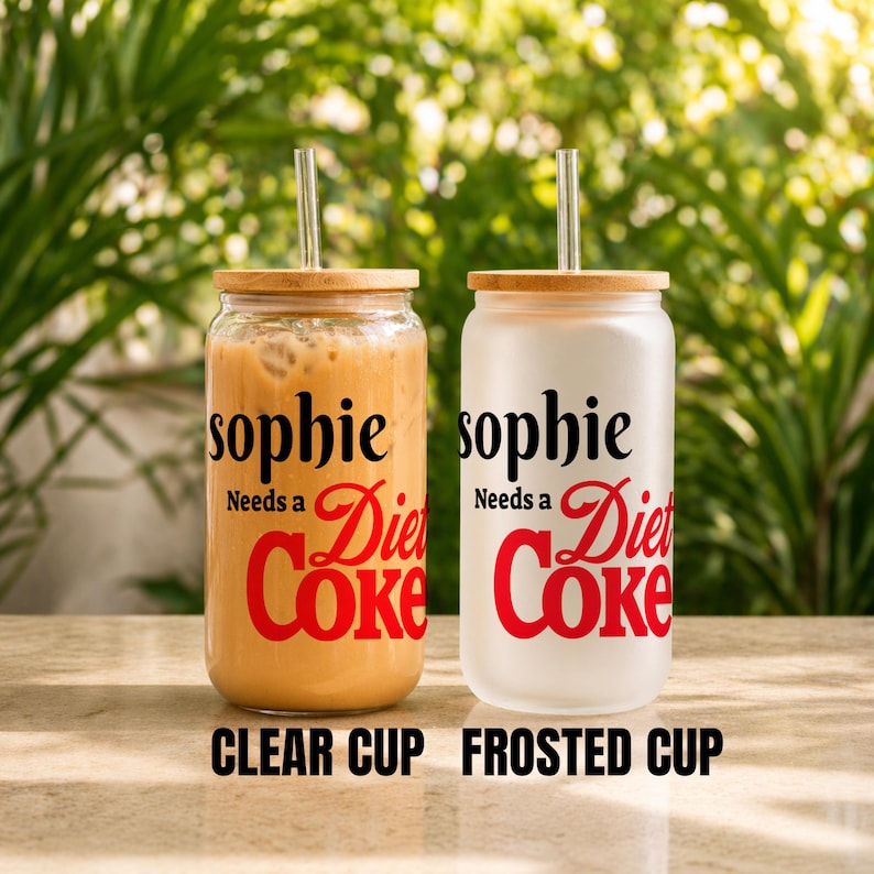May include: Two glass tumblers with bamboo lids and metal straws. One is clear and filled with a beverage, the other is frosted. Both have the text "sophie Needs a Diet Coke" in black and red. The bottom of the image reads "CLEAR CUP FROSTED CUP".