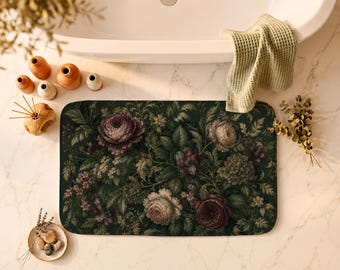 Puede incluir: Una alfombrilla de baño rectangular con fondo verde oscuro y un estampado botánico denso y detallado de varias flores, incluyendo grandes rosas moradas y blancas, flores más pequeñas y follaje verde exuberante con esquinas redondeadas.