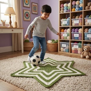 May include: A large, star-shaped crochet rug featuring alternating concentric bands of olive green and cream yarn. The rug lies flat on a textured beige carpet, serving as a play surface for a soccer ball. The design consists of a six-pointed star.