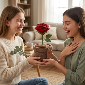 Puede incluir: Una rosa roja hecha a mano en un tiesto marrón. La rosa tiene hojas verdes y se presenta como un regalo. El tiesto tiene una etiqueta que dice "Rose's Handmade Gifts".