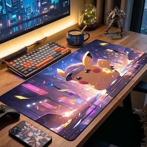 Puede incluir: Alfombrilla de escritorio rectangular con un diseño de Pikachu en un paisaje urbano colorido. La alfombrilla está rodeada por un teclado, un controlador y una funda de teléfono, creando una configuración de juego.