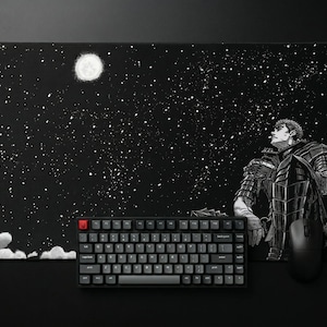 Può includere: Un tappetino da scrivania rettangolare con un'illustrazione in bianco e nero di un guerriero in armatura che guarda una luna luminosa in un cielo notturno stellato. Una tastiera meccanica nera con tasto escape rosso e un mouse nero sono posizionati sopra.