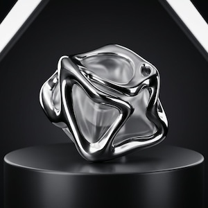 May include: A polished silver-toned metallic object with a complex, fluid, and organic shape. The structure features interconnected, rounded, and hollowed-out sections that create a continuous, sculptural form with reflective surfaces.