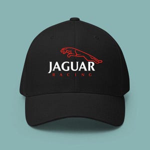 May include: A black baseball cap featuring the Jaguar Racing logo embroidered on the front. The design includes a red leaping jaguar outline above the white text JAGUAR and the smaller red text RACING centered below the main brand name.