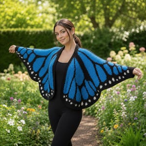 May include: A blue and black butterfly wing-shaped cardigan. The cardigan features a vibrant blue color with black accents and white dot details along the edges, resembling a butterfly's wings. The garment is open-fronted and appears to be knitted or crocheted.