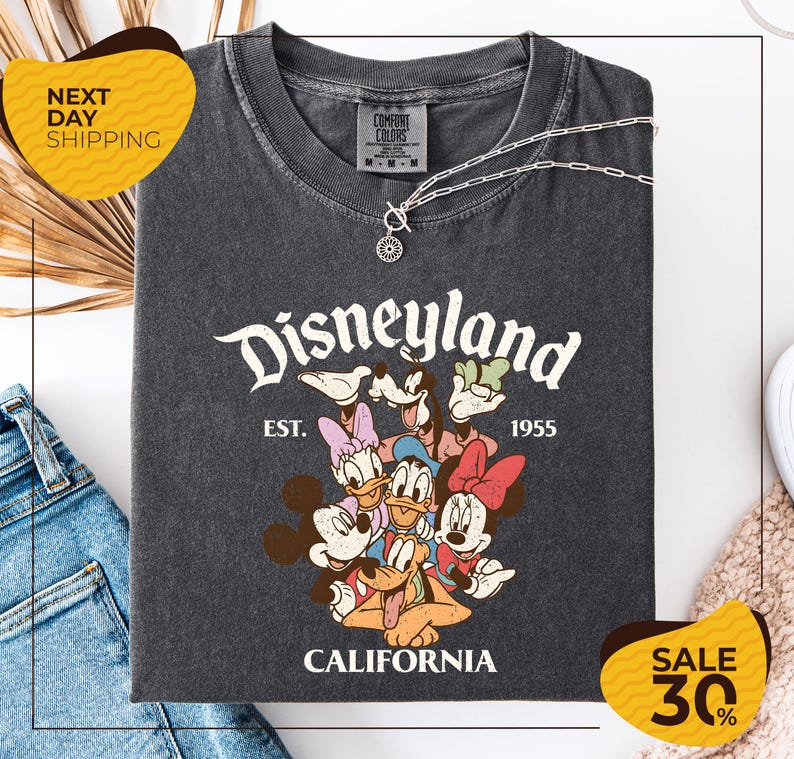 a gray t-shirt with a Disney-themed graphic, including Mickey Mouse, Minnie Mouse, Donald Duck, and Goofy. The t-shirt is displayed on a white background, and there are yellow and black sale signs indicating a 30% discount.