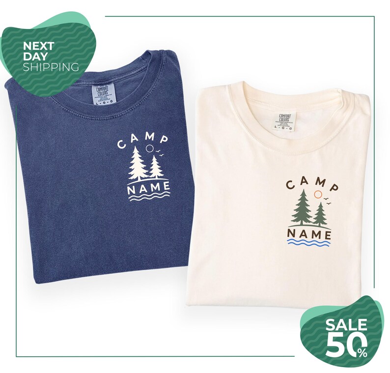 two t-shirts with the same design, one blue and one white, both featuring the text "CAMP NAME" and a graphic of trees. The t-shirts are folded and placed side by side, with a green and white sale banner in the background.