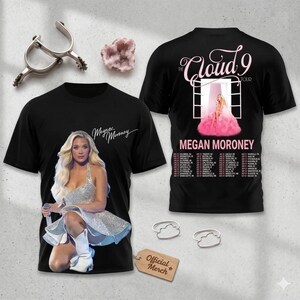 May include: Black t-shirts featuring singer Megan Moroney. One shirt displays a photo of Moroney in a silver dress, the other has "The Cloud 9 Tour" text and a tour date list. The shirts have the words "Megan Moroney" on them.