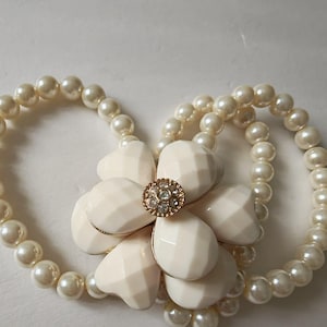 Bracciale vintage elasticizzato a tre fili con perle finte e grande decorazione floreale.