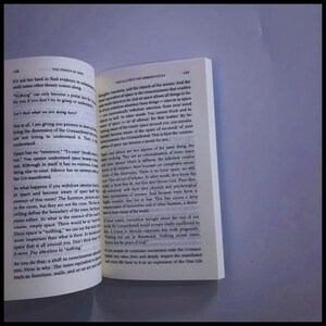 May include: An open book with white pages and black printed text. The left page is numbered 138 and titled The Power of Now, while the right page is numbered 139 and titled Portals into the Unmanifested. The text discusses consciousness, space, and silence.