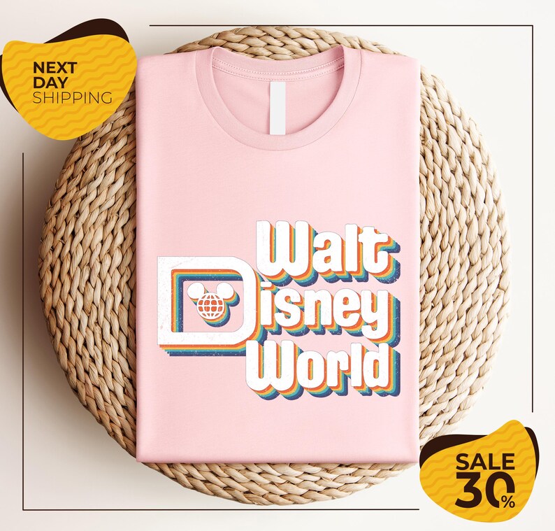 A pink t-shirt with the text "Walt Disney World" printed on it, placed on a woven basket. There are two yellow sale signs in the image, one on the left and one on the right, indicating a 30% discount on the item.