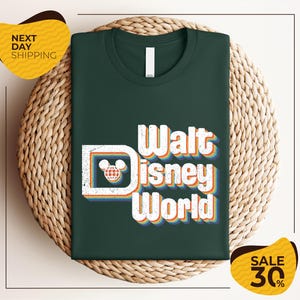 A green t-shirt with the text "Walt Disney World" printed on it, displayed on a woven basket.