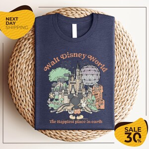 A t-shirt with a graphic design featuring various Disney landmarks and the text "Walt Disney World" is displayed on a woven placemat.