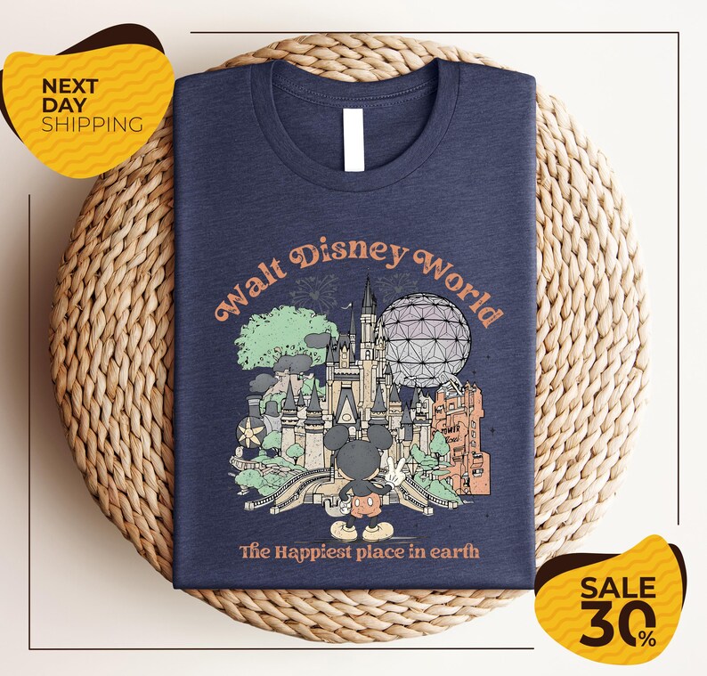 A t-shirt with a graphic design featuring various Disney landmarks and the text "Walt Disney World" is displayed on a woven placemat.