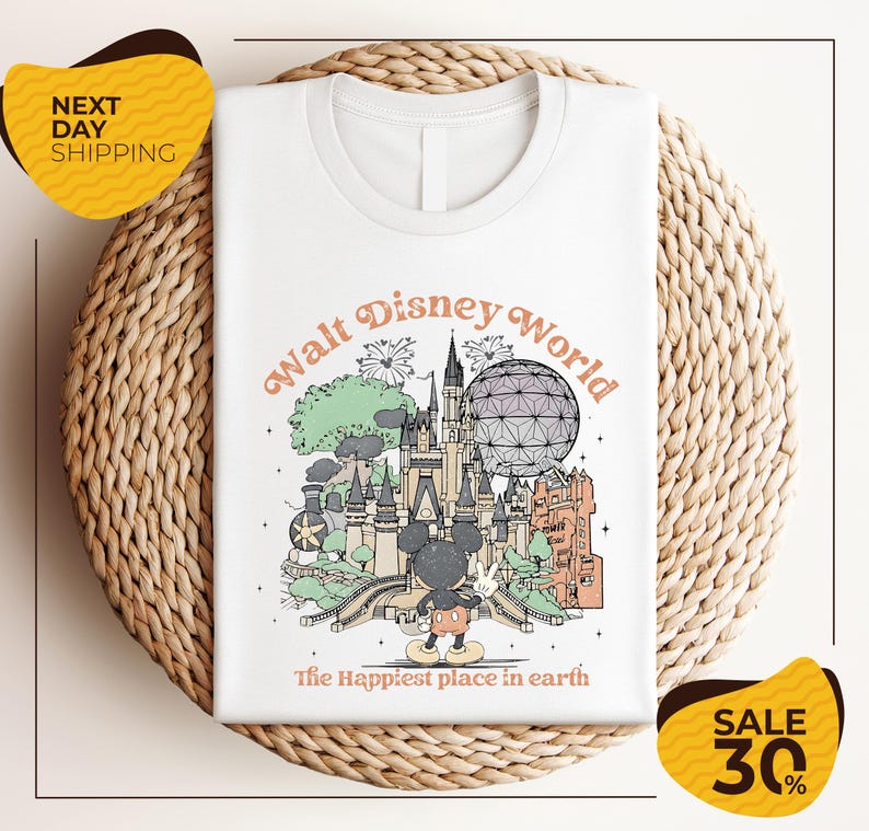 A white t-shirt with a graphic design depicting various Disney landmarks and elements, including Mickey Mouse and the Eiffel Tower, along with the text "Walt Disney World" and "The Happiest place in earth".
