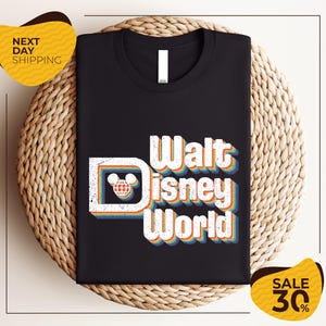 A black t-shirt with the text "Walt Disney World" printed on it, along with a Mickey Mouse logo. The t-shirt is displayed on a woven basket, and there are yellow price tags indicating a sale of 30% off.