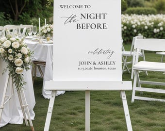 Pode incluir: Placa de boas-vindas branca em cavalete, adornada com arranjos florais. A placa diz "WELCOME TO the NIGHT BEFORE celebrating JOHN & ASHLEY 11.17.2026 | houston, texas". A placa está em um gramado, com uma mesa e cadeiras ao fundo.