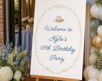 Pode incluir: Um cavalete de madeira exibe uma placa branca com o texto "Welcome to Kylie's 18th Birthday Party" em escrita azul marinho. A placa é emoldurada por um design floral dourado e uma ilustração de xícara de chá. A cena inclui arranjos florais e balões.