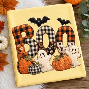 May include: A pale yellow fabric featuring a decorative applique design that spells the word BOO. The letters are crafted from orange and black buffalo plaid and floral fabric. Two black bats, two white ghosts, and two pumpkins are included.