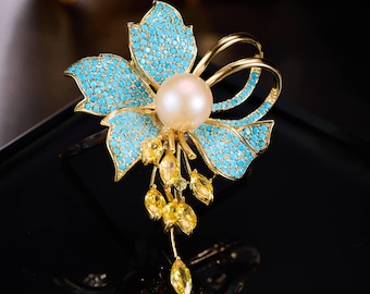 Broche de perlas con forma de flor azul, broche floral con aspecto turquesa, joyería llamativa en tono dorado.