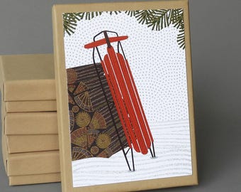 May include: A red and black sled with a wooden base sits in a snowy scene. The sled is leaning against a stack of logs with a brown and gold patterned design. The background is a white snowy scene with a light grey dotted pattern.