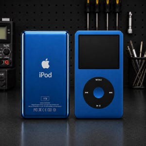 May include: A blue Apple iPod digital music player shown from the front and back. The front features a black screen and a circular click wheel. The back displays the Apple logo, the text iPod, a 1TB storage label, and regulatory markings.