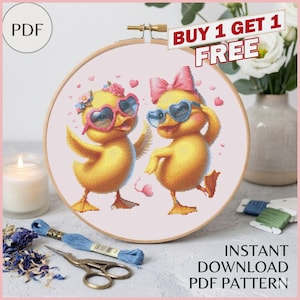 Könnte beinhalten: Ein Kreuzstichmuster in einem Holzrahmen zeigt zwei gelbe Entenküken mit herzförmigen Sonnenbrillen und Schleifen. Das Design enthält den Text "BUY 1 GET 1 FREE" und "INSTANT DOWNLOAD PDF PATTERN". Stickgarn, eine Schere und eine Kerze sind ebenfalls zu sehen.