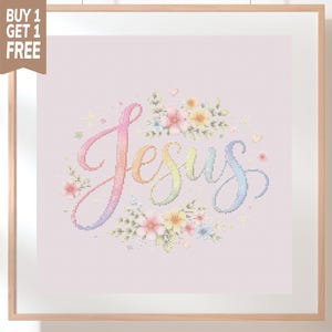 May include: A cross-stitch pattern featuring the word Jesus in a gradient rainbow script font, surrounded by small pastel-colored floral arrangements of pink, yellow, and blue flowers, all set against a light pink grid background in a wooden frame.