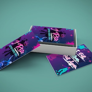 May include: A white box containing business cards with a purple, pink, and teal design. The cards feature the text "I Rise After Every Fall" in a stylized font, along with graphic elements. Two cards are outside the box, displaying the same design.