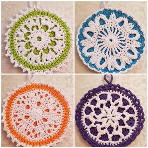 May include: Four crocheted pot holders in different colors. The pot holders are round and have a white center with a crocheted design. The colors are green, blue, orange, and purple.