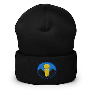 May include: Black beanie with a folded brim. The beanie features a circular embroidered patch with a yellow microphone design, blue background, and black mountain silhouettes. A warm and stylish winter accessory.