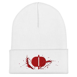 May include: White beanie hat with a red graphic design. The design features a stylized shape with a vertical line and splatter details. The hat is made of a soft, knitted material.