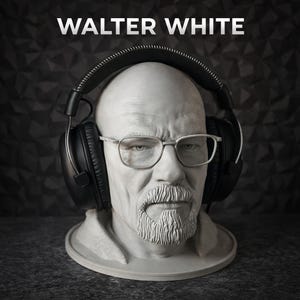 May include: A light grey bust of a bald man with a goatee and glasses, wearing large black over-ear headphones. The text WALTER WHITE is printed in white capital letters above the head. The sculpture features detailed facial features and texture.
