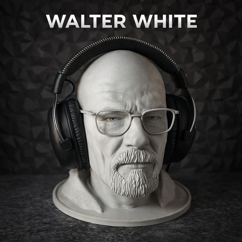 May include: A light grey bust of a bald man with a goatee and glasses, wearing large black over-ear headphones. The text WALTER WHITE is printed in white capital letters above the head. The sculpture features detailed facial features and texture.