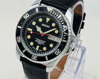 Reloj automático Seiko 5 vintage: esfera negra, fecha y día, restaurado en la década de 1990, fondo transparente.