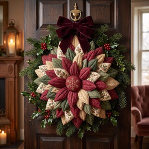 May include: A fabric wreath featuring layered, quilted petals in shades of deep red, sage green, and cream with floral patterns. A dark red velvet bow sits at the top, and a central button displays a gold embroidered snowflake design.