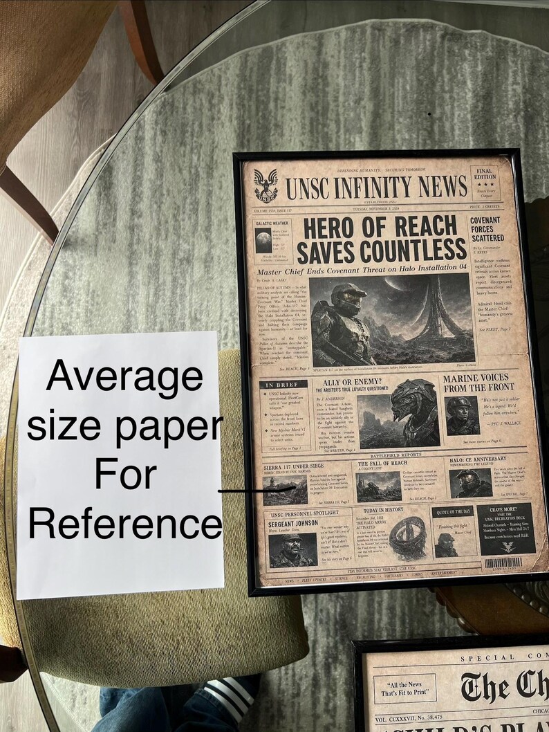May include: A framed newspaper print titled UNSC INFINITY NEWS with a sepia-toned vintage aesthetic. The headline reads HERO OF REACH SAVES COUNTLESS, featuring illustrations of Master Chief and Covenant characters alongside various news columns.