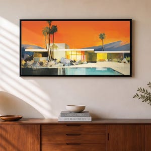 May include: A rectangular wall art print in a black frame depicting a mid-century modern house with a flat roof, large windows, and a swimming pool. The scene features tall palm trees, rocky landscaping, and a vibrant orange sunset sky.