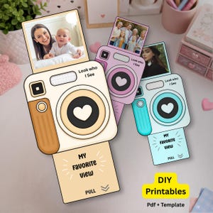 Puede incluir: Un conjunto de tarjetas imprimibles DIY con forma de cámara en beige, rosa y azul. Cada tarjeta presenta una foto, el texto "Look who I See" y "My Favorite View". Las tarjetas tienen un diseño de corazón y el texto "PULL".
