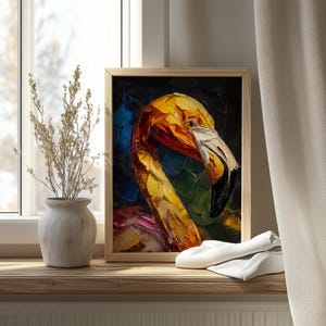 Op de afbeelding: Een ingelijst olieverfschilderij van een flamingo. Het kunstwerk toont een close-up van de kop en nek van de vogel, met levendige penseelstreken in tinten geel, oranje, rood en groen tegen een donkere achtergrond. De snavel van de flamingo is wit en het schilderij zit in een houten lijst.